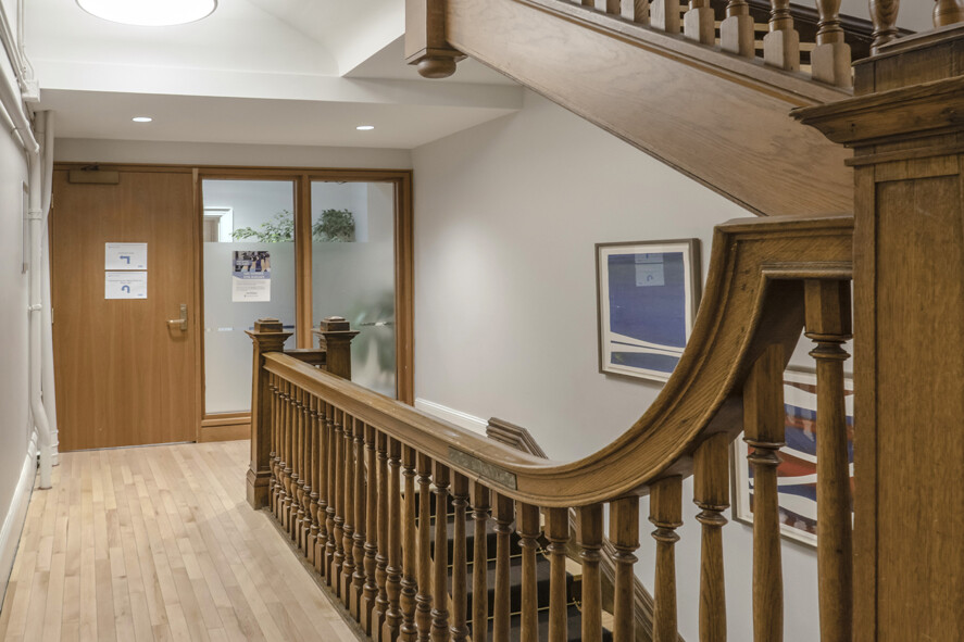 Large wood staircase connecting first, second and third floor with wood door and windows