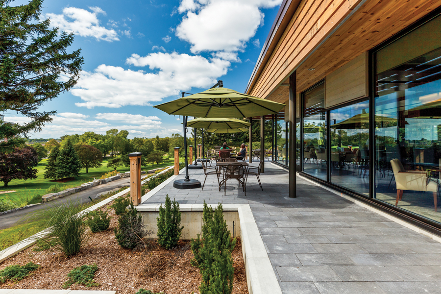 Outdoor patio seating with landscaping looking through to glazed of dining lounge