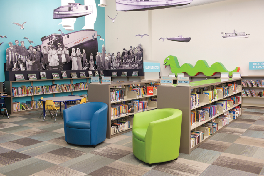 Bookshelves with historic photo wall mural, table and chairs for kids and blue and green armchairs