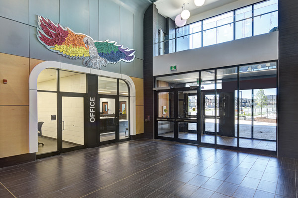Double height entry lobby with red, blue and yellow light fixtures and colourful hawk mascot