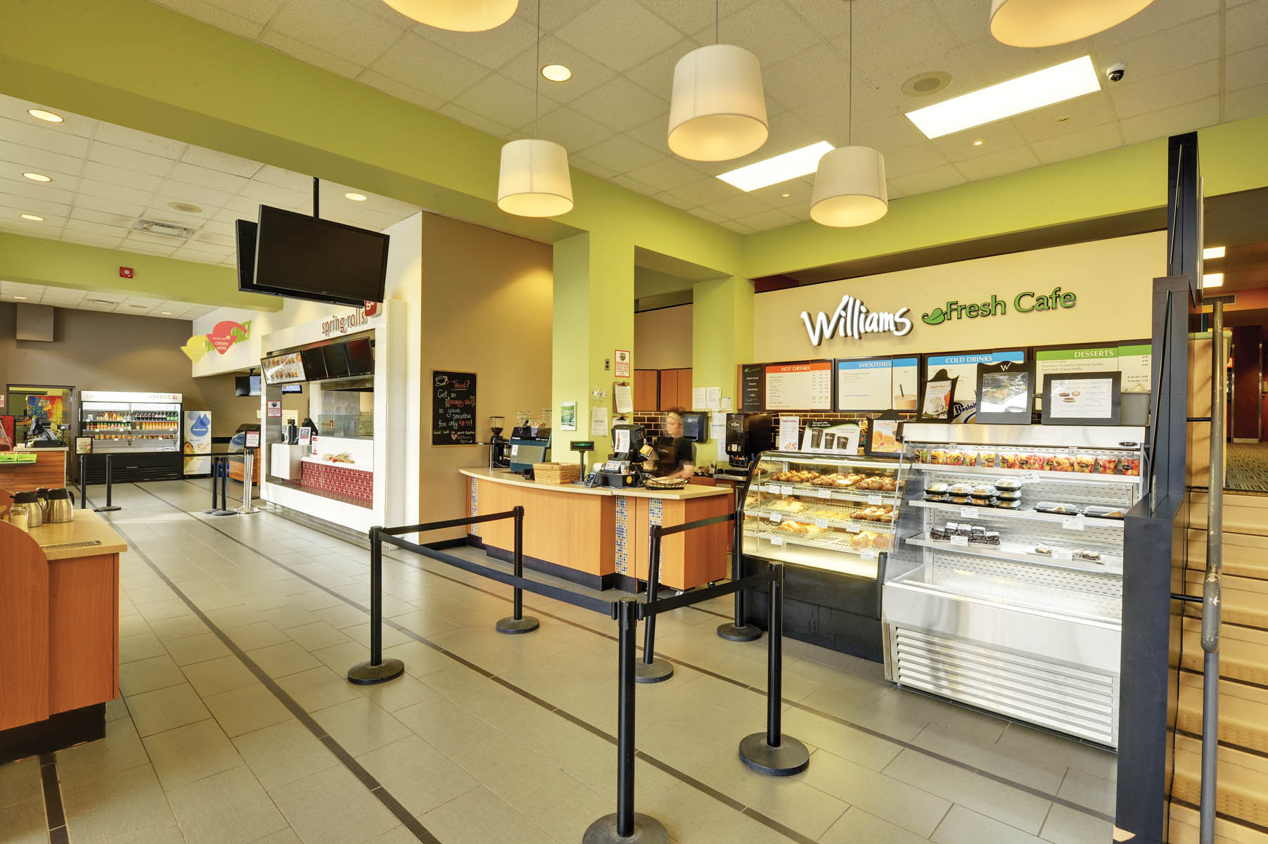 Williams Fresh Cafe counter with pastry display case, light green walls and white pendant light fixtures