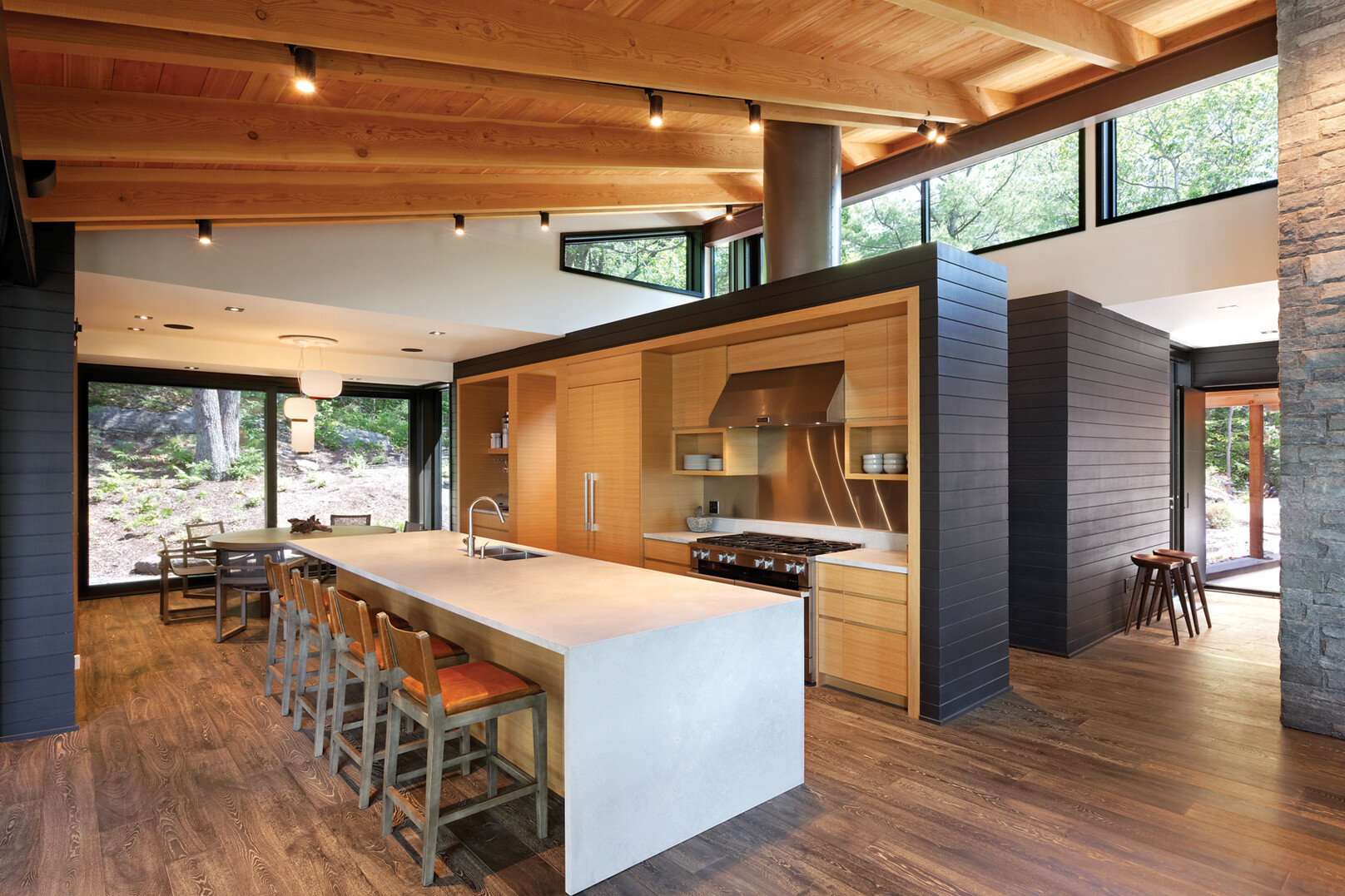 Wood millwork kitchen with large white island and slanted wood rafter ceiling and clerestrory windows