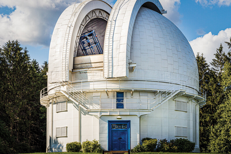 White observatory with blue door on a sunny day with dome open